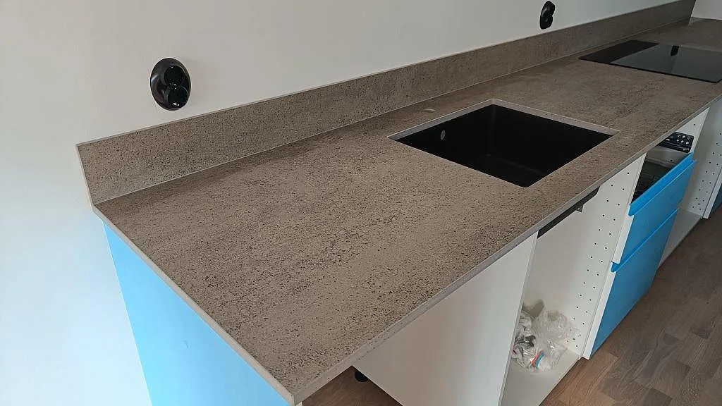 Köksbänkskiva i grå Dekton Keon, matt keramik, med svart underlimmad diskho och stänkkant i Veberöd.