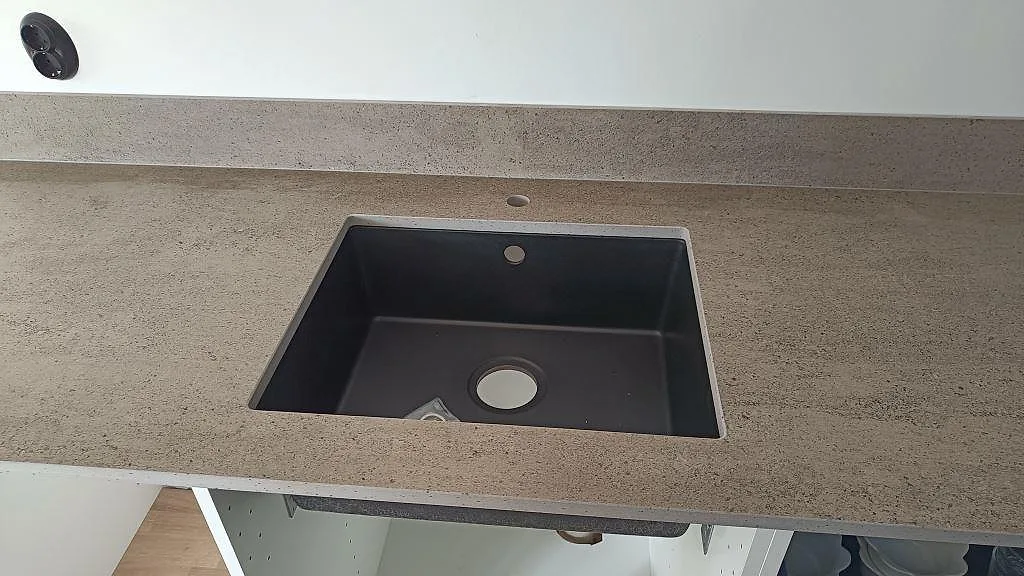 Detalj av svart underlimmad diskho i en matt Dekton Keon bänkskiva med stänkkant i Veberöd.