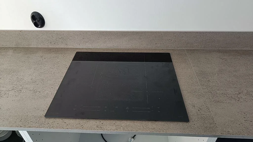 Infälld häll i en matt Dekton Keon köksbänkskiva med grå stänkkant i Veberöd.