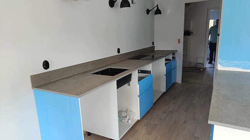 Lång köksbänkskiva i Dekton Keon, matt, med vit stomme och blå skyddsfilm i Veberöd.
