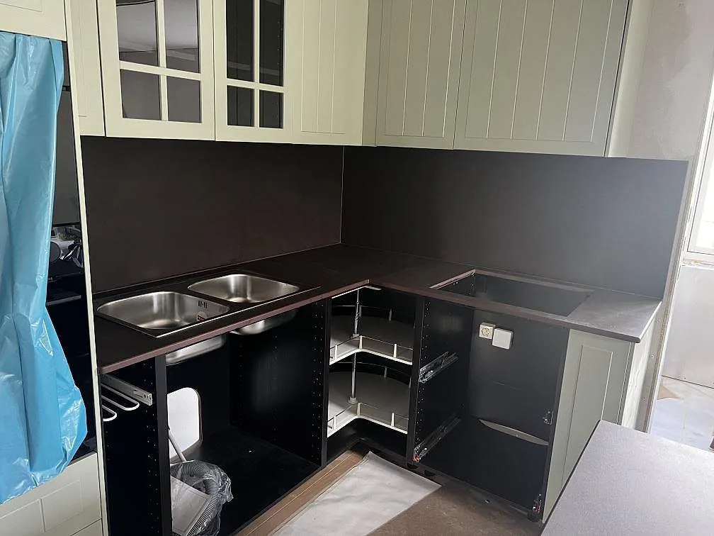 L-format kök i Alingsås med matt köksbänkskiva i Dekton Keranium, mörkt stänkskydd, rostfri dubbelho och hällöppning under montering.