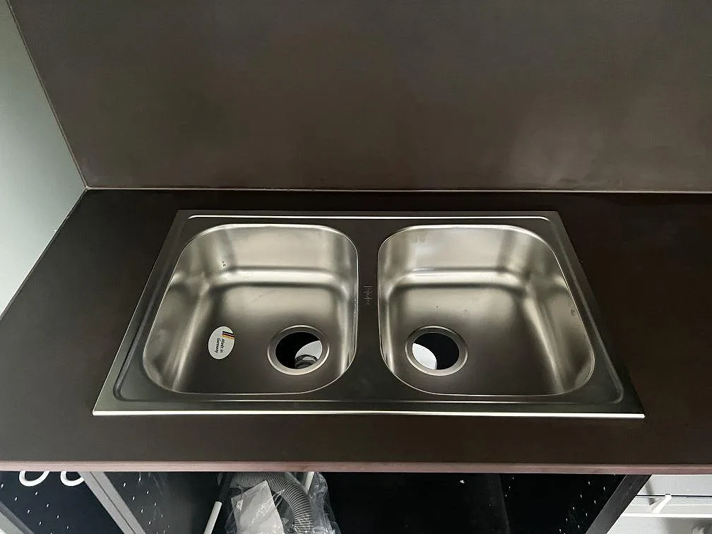 Närbild på matt Dekton Keranium med rostfri dubbelho och mörkt stänkskydd i ett kök i Alingsås.