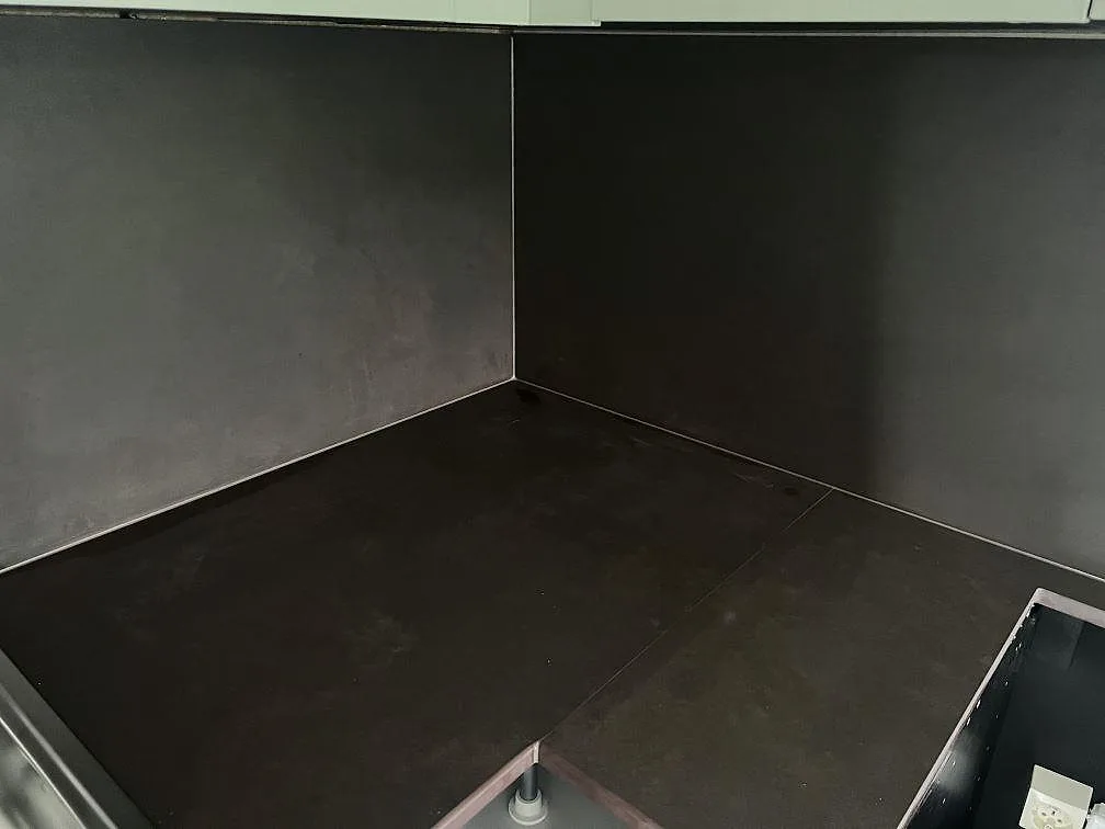 Hörndel av L-formad köksbänkskiva i matt Dekton Keranium med matchande mörkt stänkskydd i Alingsås.
