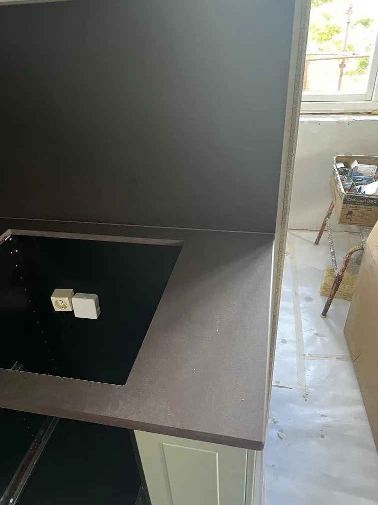 Sidovy av matt Dekton Keranium med hällöppning, väggskiva och fönsterljus i ett kök i Alingsås.