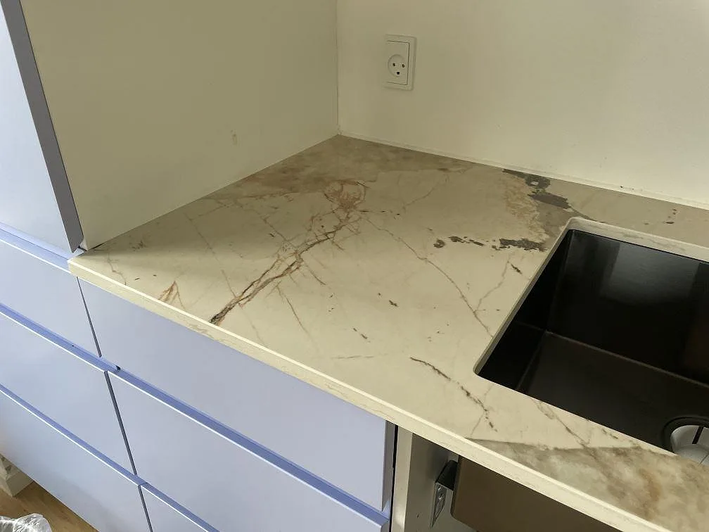 Närbild på bänkskiva i polerad Dekton Khalo keramik med marmorerad ådring vid diskhon i København.