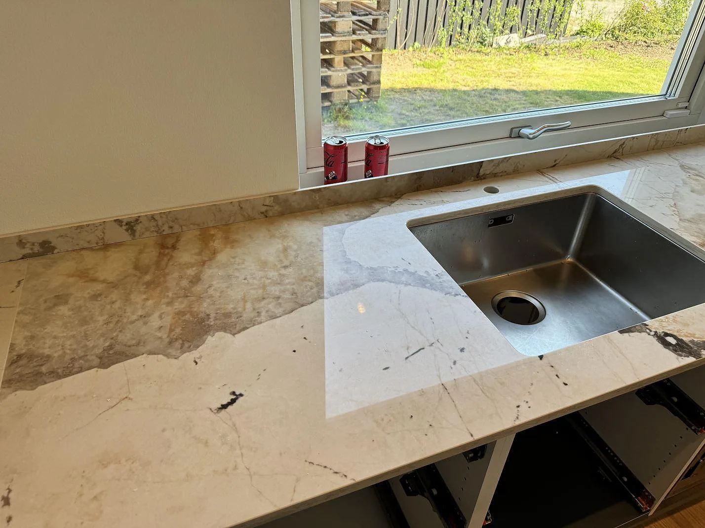 Polerad Dekton Khalo bänkskiva med diskho under fönster och marmorerad ljus yta i ett kök i Malmö.