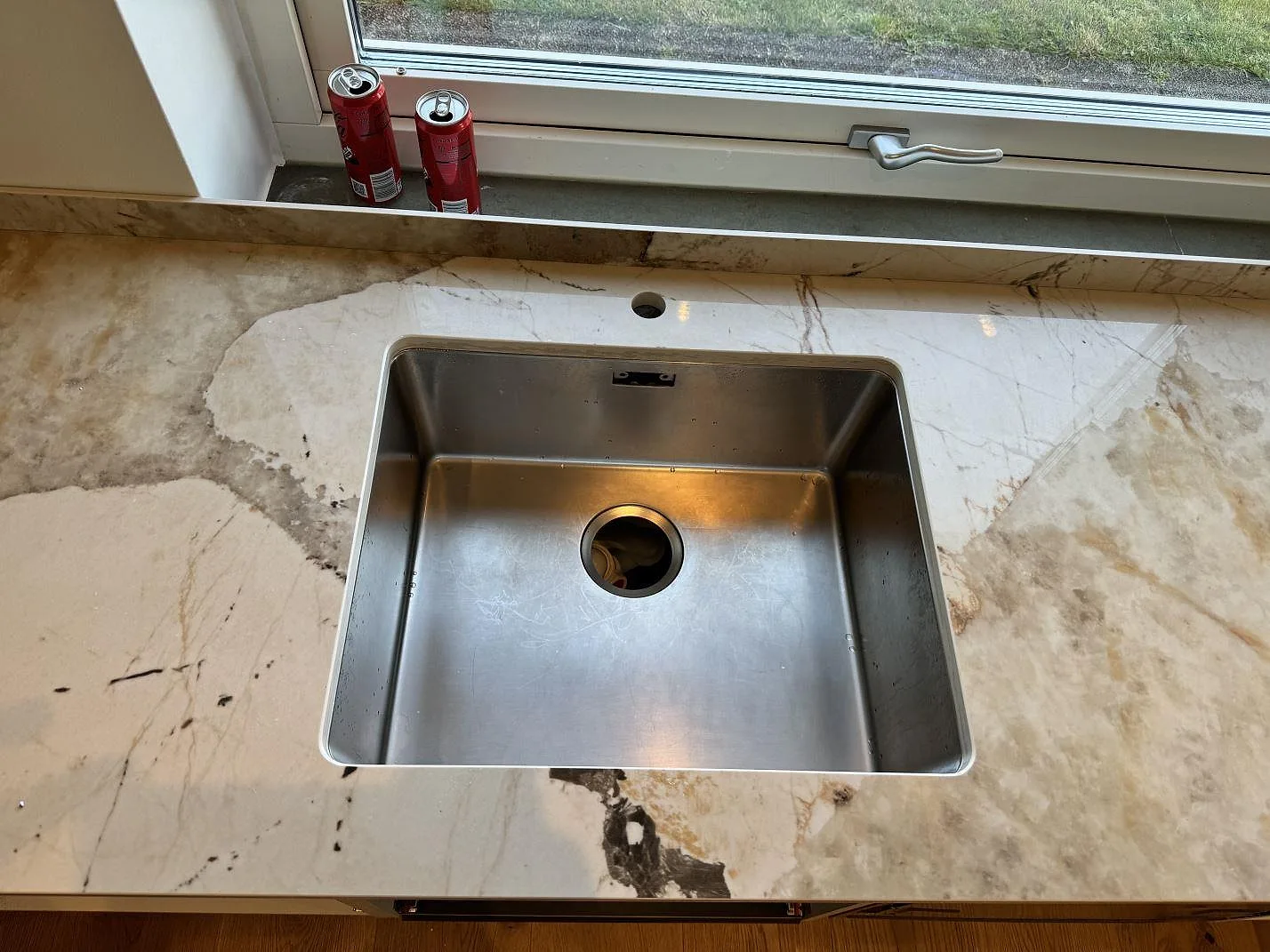 Diskbänksyta i polerad Dekton Khalo med rostfri diskho, låg stänkkant och fönster i ett kök i Malmö.