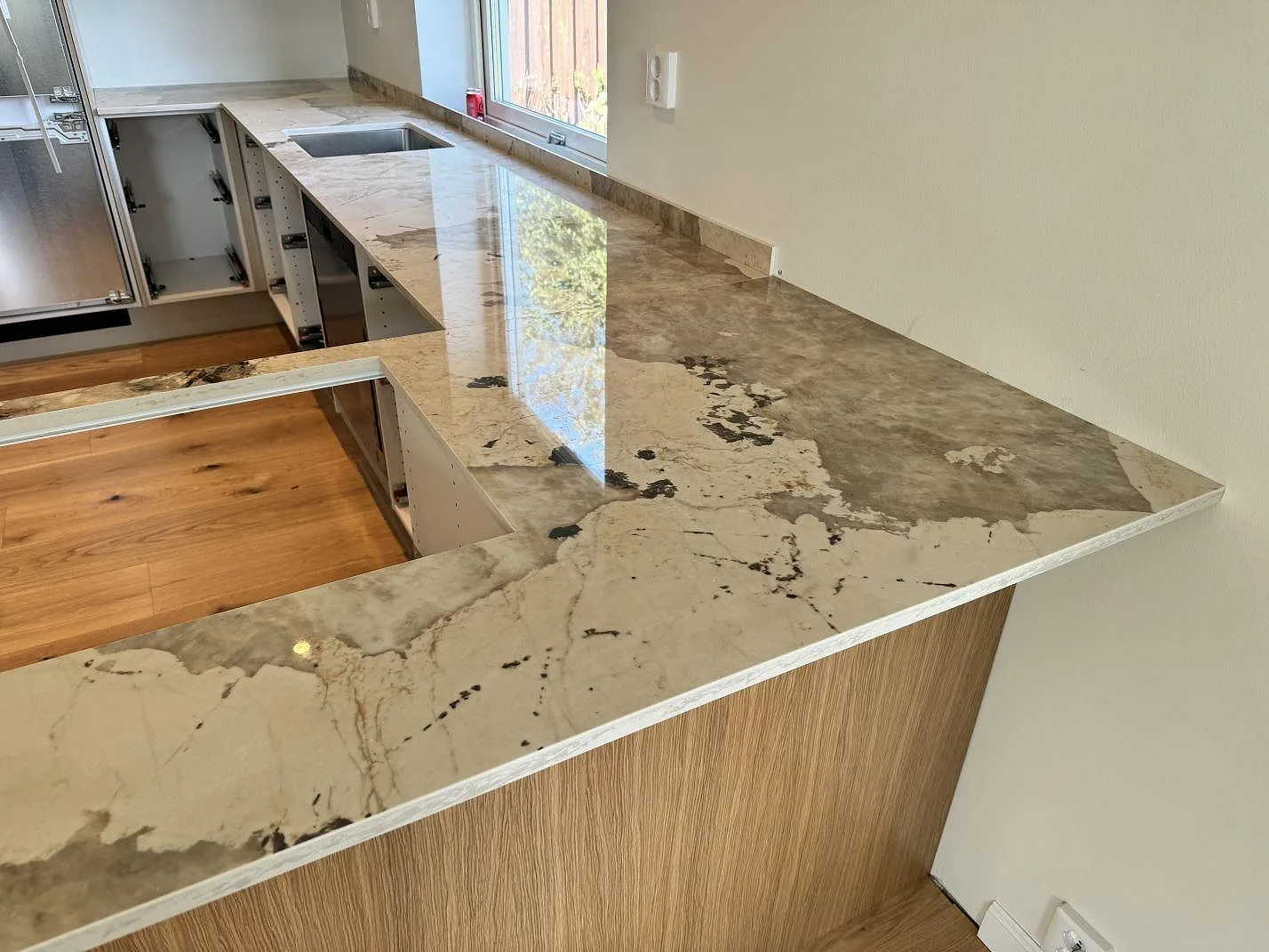 Blank Dekton Khalo som köksbänkskiva på halvö med synligt urtag och arbetsyta mot fönster i ett kök i Malmö.