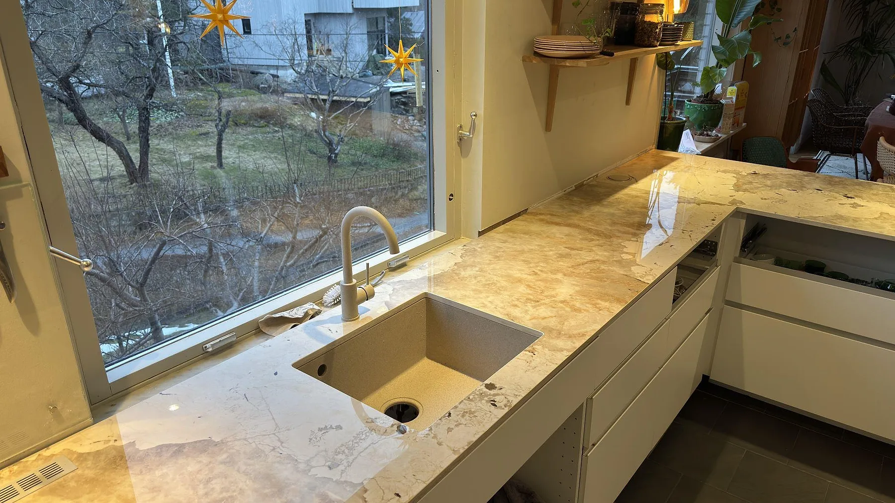 Köksbänkskiva i Dekton Khalo i Nacka med underlimmad diskho och hög mässingsblandare framför fönstret, fotat under montering.