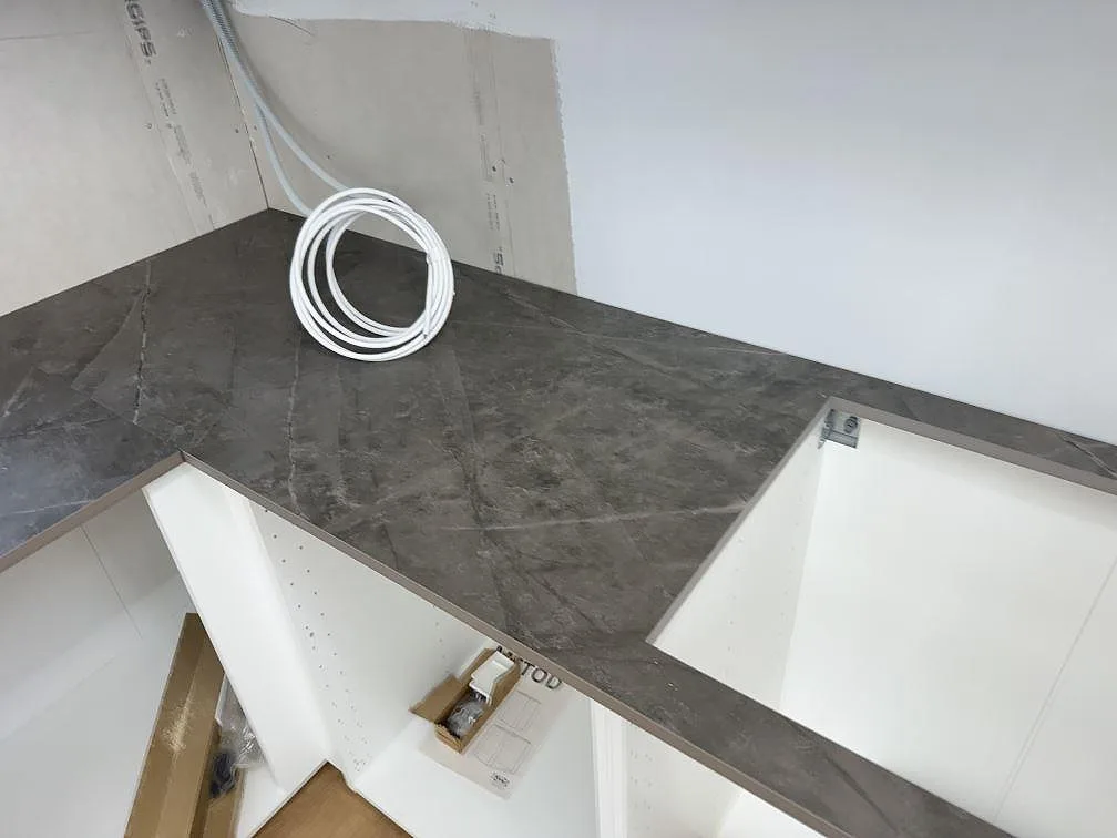 Yta i grå Dekton Kira med mjuk marmorlik ådring på köksbänkskivan under montering i Immeln.
