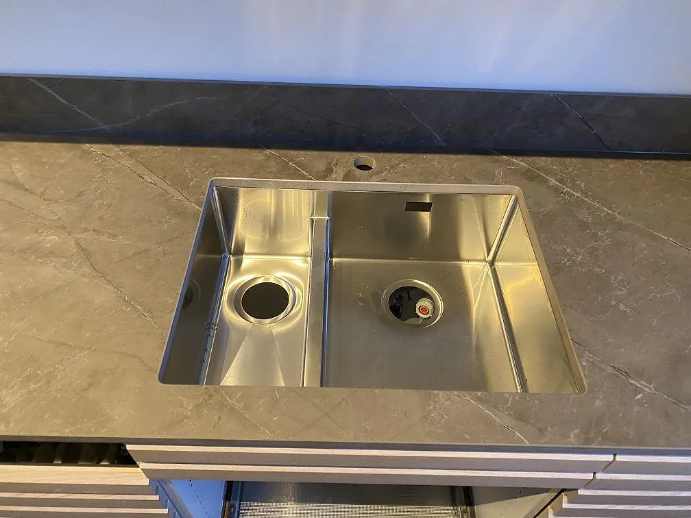 Rostfri diskho monterad i en matt Dekton Kira bänkskiva med grå ådring och stänkskydd i Kungsbacka.
