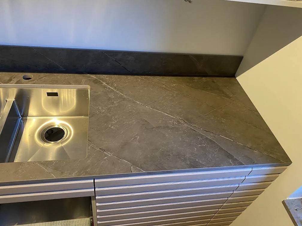 Detalj av matt Dekton Kira köksbänkskiva vid diskhon med sammanhängande grå ådring i Kungsbacka.