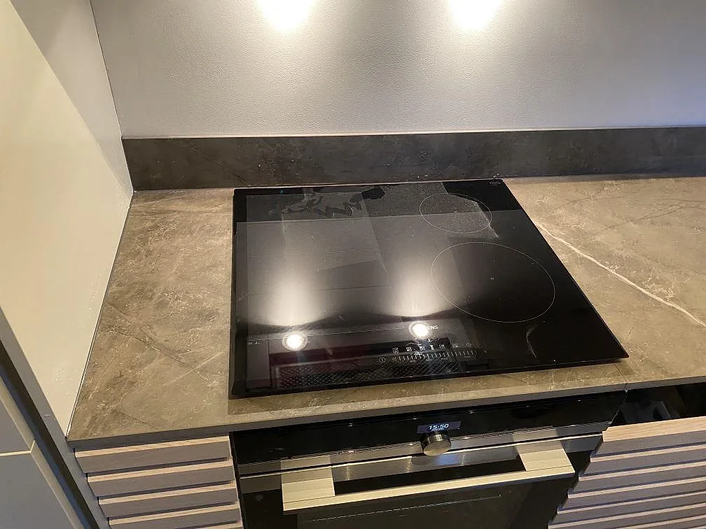 Svart induktionshäll på matt köksbänkskiva i Dekton Kira med lågt stänkskydd i Kungsbacka.