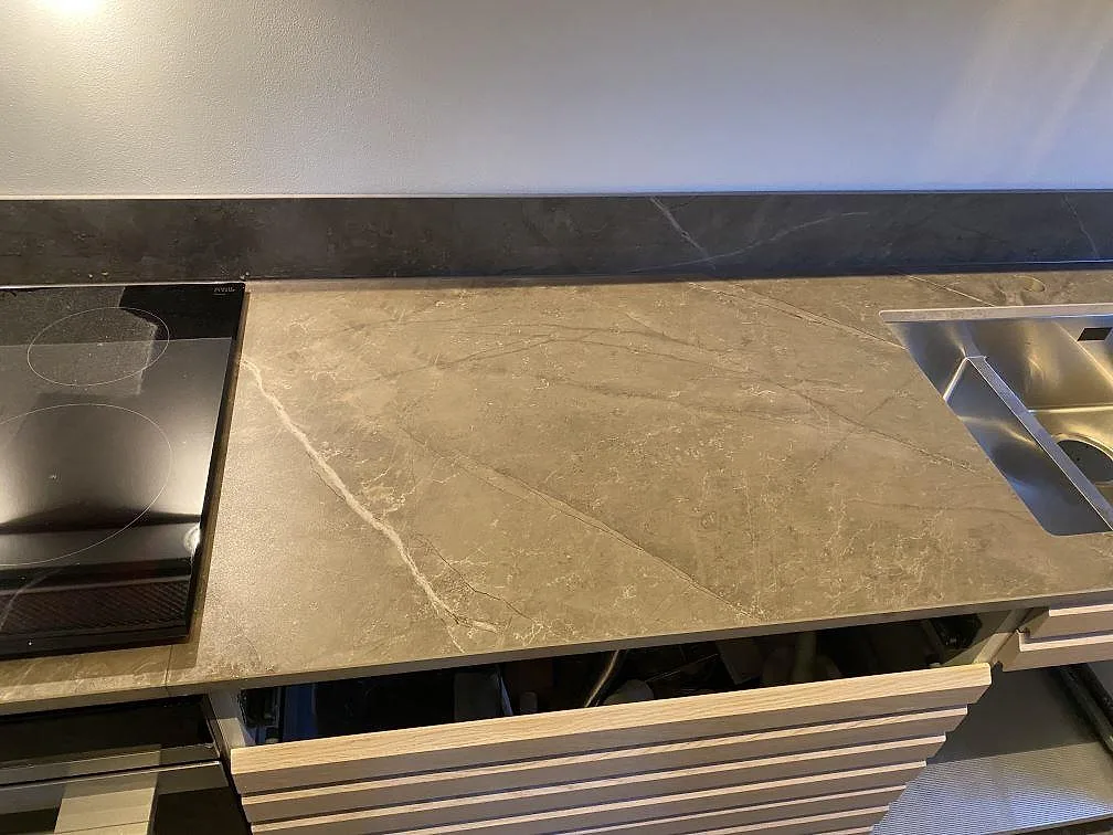 Närbild på matt köksbänkskiva i Dekton Kira med svart häll, rostfri diskho och ljus ådring i Kungsbacka.
