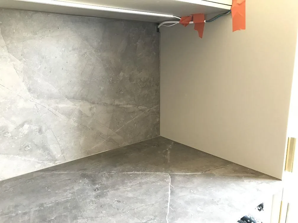 Bänkskiva och uppvikt stänkskydd i grå Dekton Kira under montering, med framdragen el, i ett kök i Malmö.