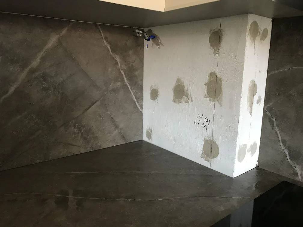 Hörn med bänkskiva och stänkskydd i matt grå Dekton Kira under montering i ett kök i Malmö.
