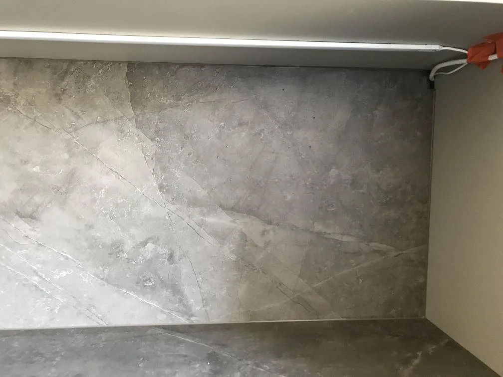 Grå Dekton Kira stänkskydd med diskret ådring ovanför bänkskivan under montering i ett kök i Malmö.