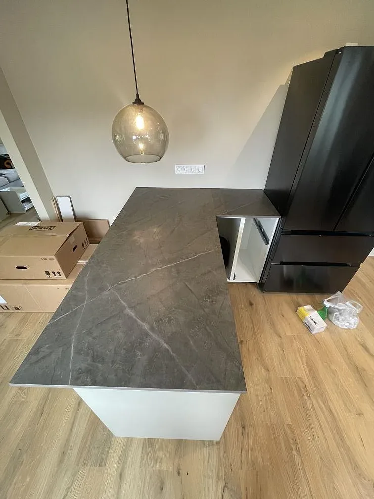 Matt köksbänkskiva i grå Dekton Kira med mjuk ådring längs en köksbänk under montering i Strängnäs.