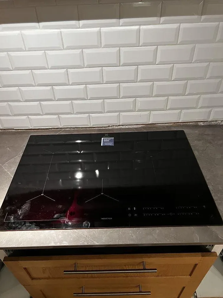 Svart induktionshäll infälld i grå polerad Dekton Korso med synlig stenådring i Arlöv.