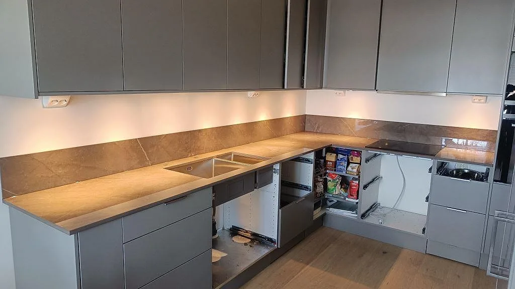 U-format kök i Göteborg med polerad Dekton Korso som bänkskiva och 8 mm stänkskydd under LED-belysning.