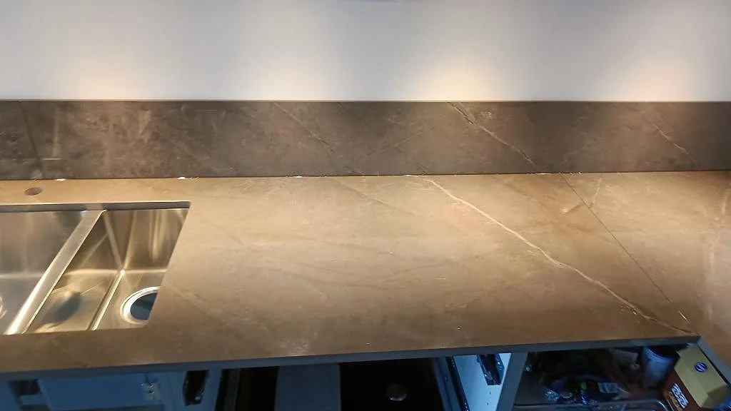 Ytdetalj av köksbänkskiva i polerad Dekton Korso med synlig ådring och rostfri diskho i Göteborg.