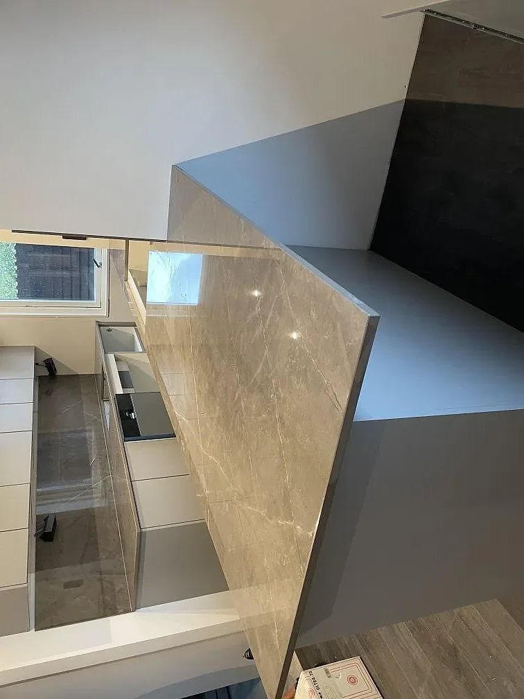 Polerad Dekton Korso bänkskiva på köksö med speglande yta, fönsterljus och vit köksinredning i Häljarp.