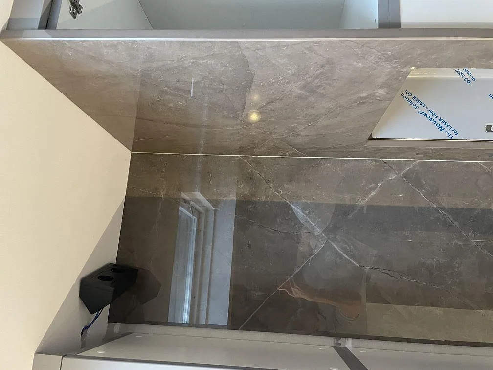 Polerad Dekton Korso bänkskiva och stänkskydd med grå ådring, blank reflektion och vit vägg i Häljarp.
