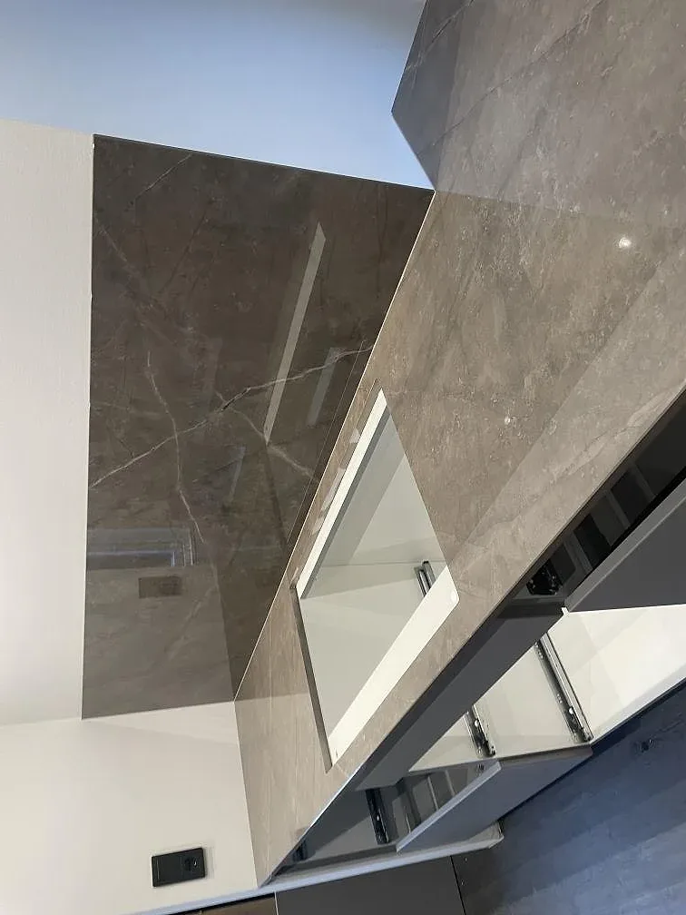 Detalj av köksö i polerad Dekton Korso med rektangulärt urtag, blank yta och väggskiva i Häljarp.