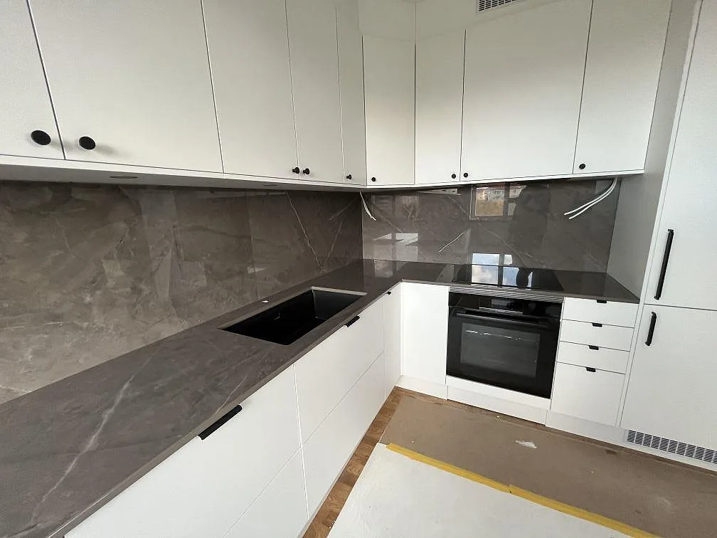 Polerad Dekton Korso som köksbänkskiva och stänkskydd med mörk arbetszon och induktionshäll i Johanneshov.