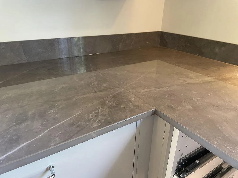 Detalj av hörnskarv i grå Dekton Korso, polerad köksbänkskiva med 8 mm stänkkant i Kullavik.