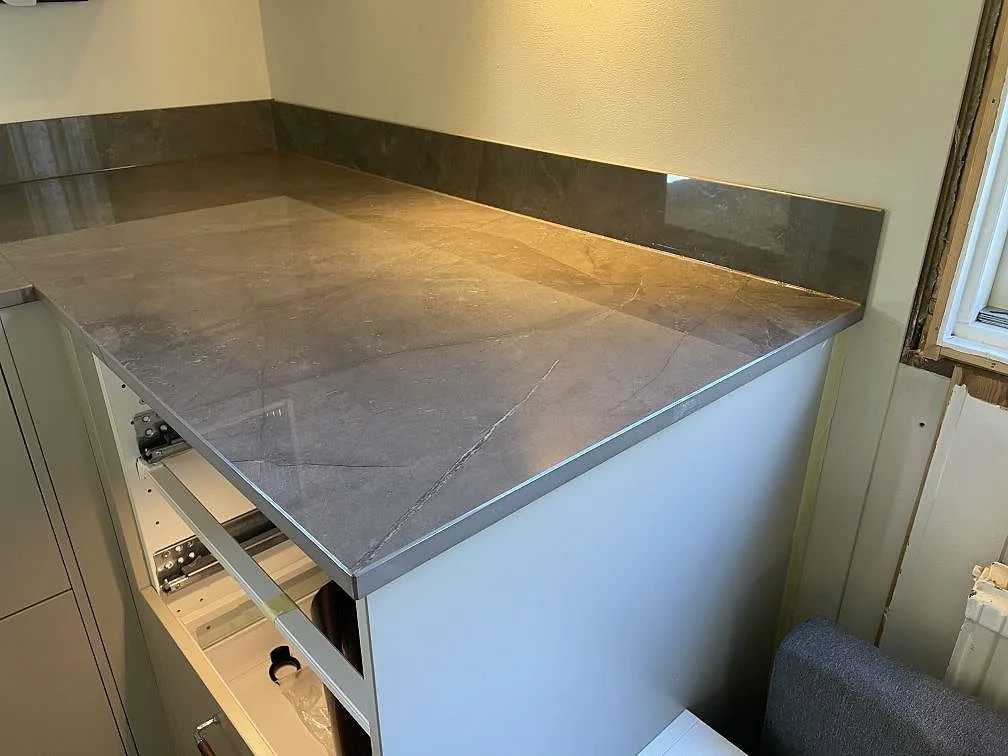 Köksbänkskiva i Dekton Korso vid fönster, polerad grå keramik med låg stänkkant i Kullavik.