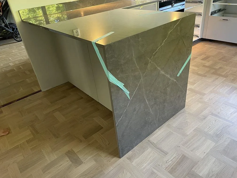 Halvö klädd med grå Dekton Korso i polerad keramik och synlig ådring i ett kök i Kullavik.