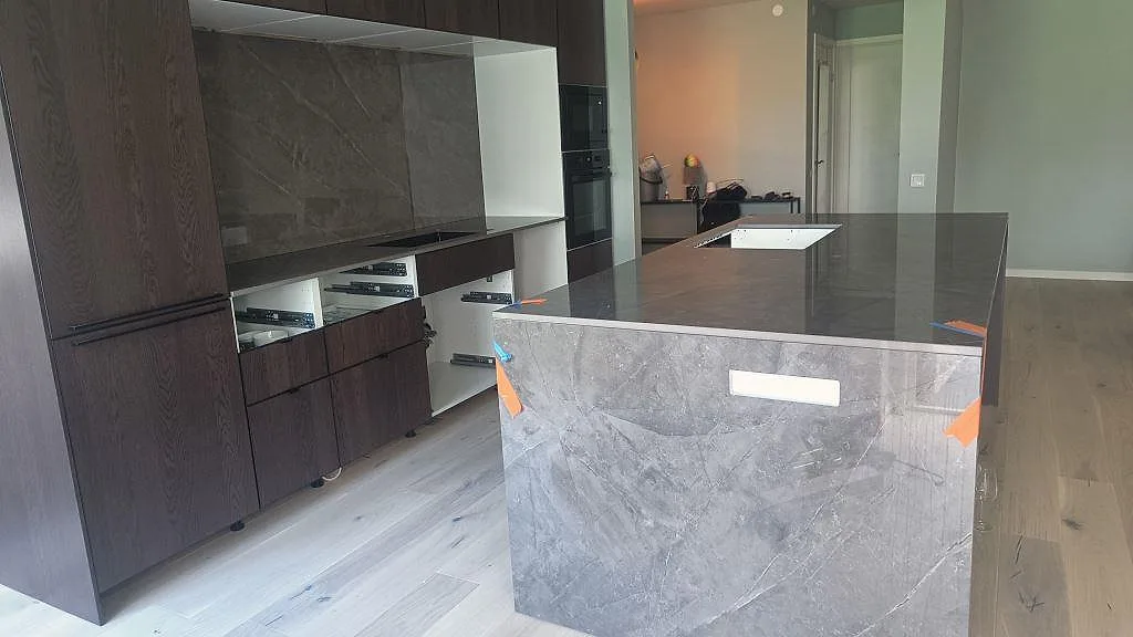 Polerad Dekton Korso som köksö med vattenfallssida och mörka köksskåp i Staffanstorp.