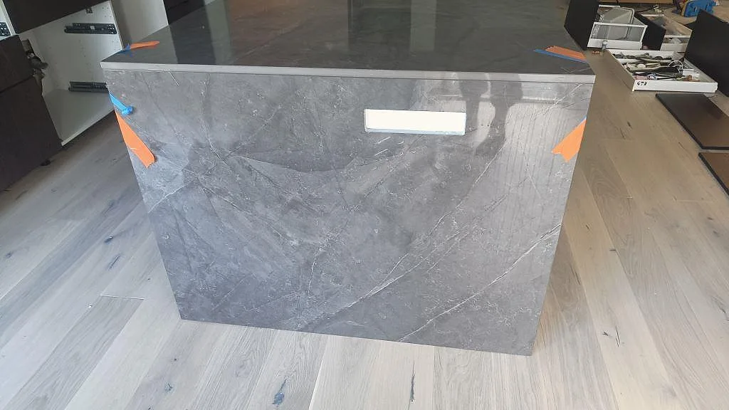Frontsida på köksö i polerad Dekton Korso med grå taupe ådring i Staffanstorp.
