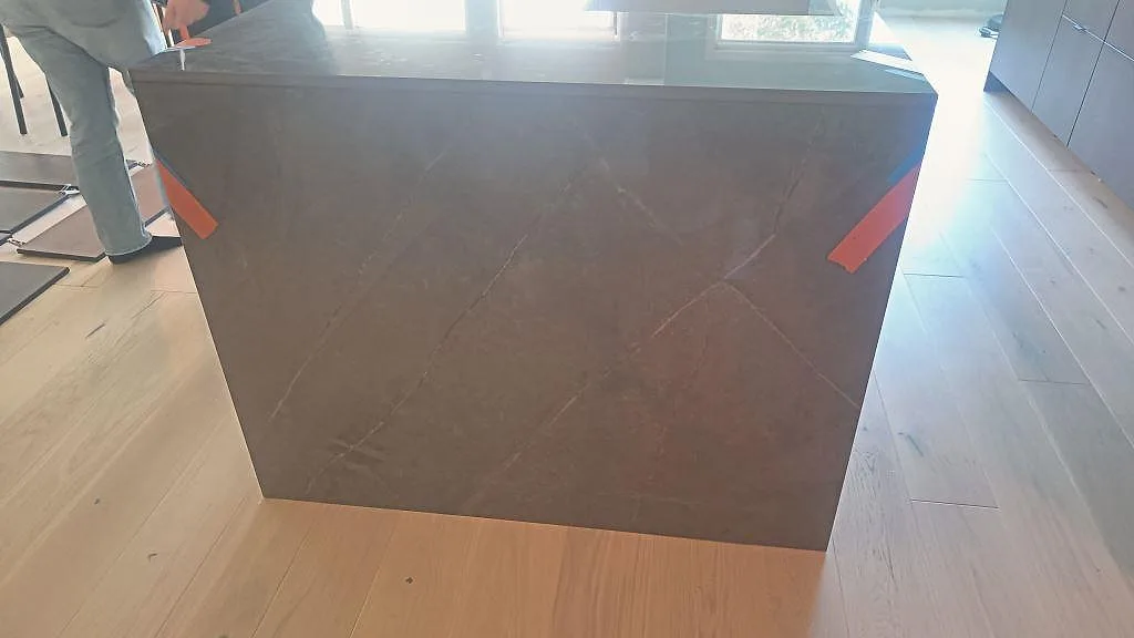 Vattenfallssida på köksö i polerad Dekton Korso under montering i Staffanstorp.