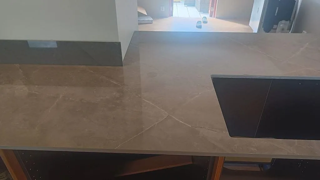 Polerad bänkskiva i Dekton Korso med häll på köksö och öppen montering i Trollhättan.