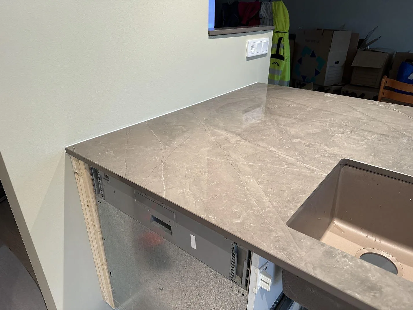 Köksö i polerad Dekton Korso med dubbel underlimmad rostfri diskho och hällöppning i ett kök i Tygelsjö.