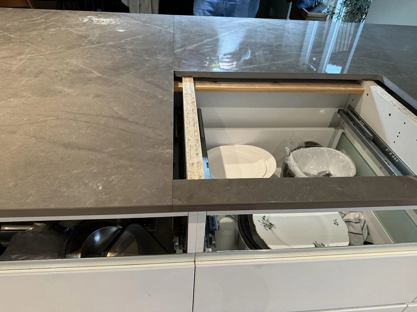 Köksbänkskiva i polerad Dekton Korso med utskärning för häll och vita köksfronter i Tygelsjö.