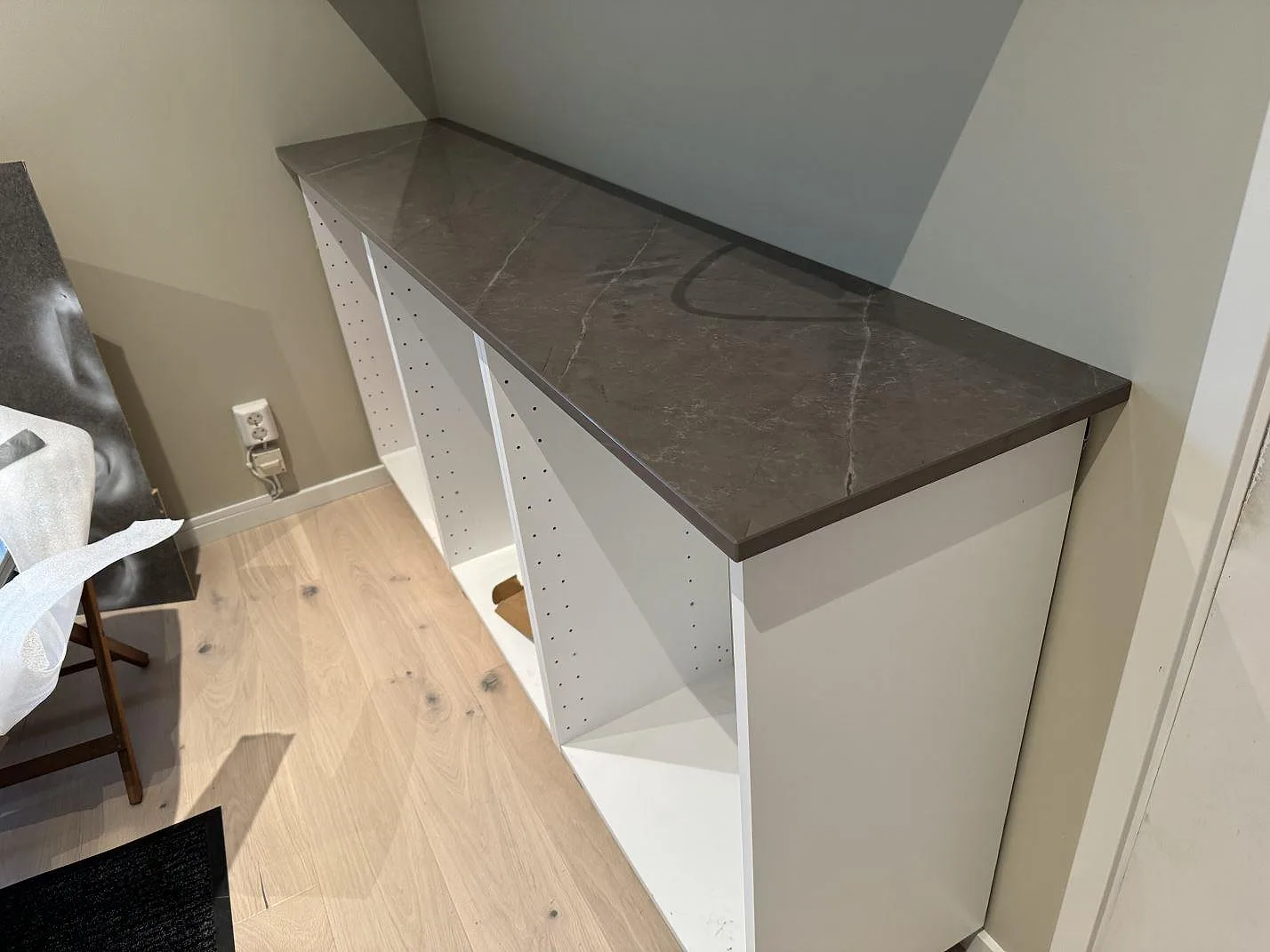 Sidobänk i polerad Dekton Korso på vita skåpstommar med träparkett i Tygelsjö.