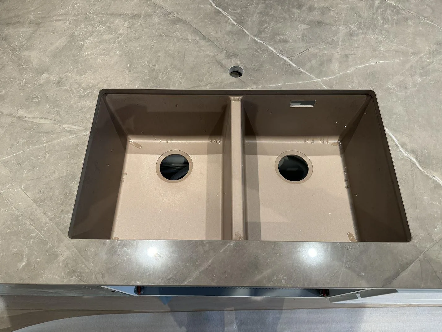 Polerad köksbänkskiva i Dekton Korso med brun-taupe ådring och underlimmad diskho i Tygelsjö.