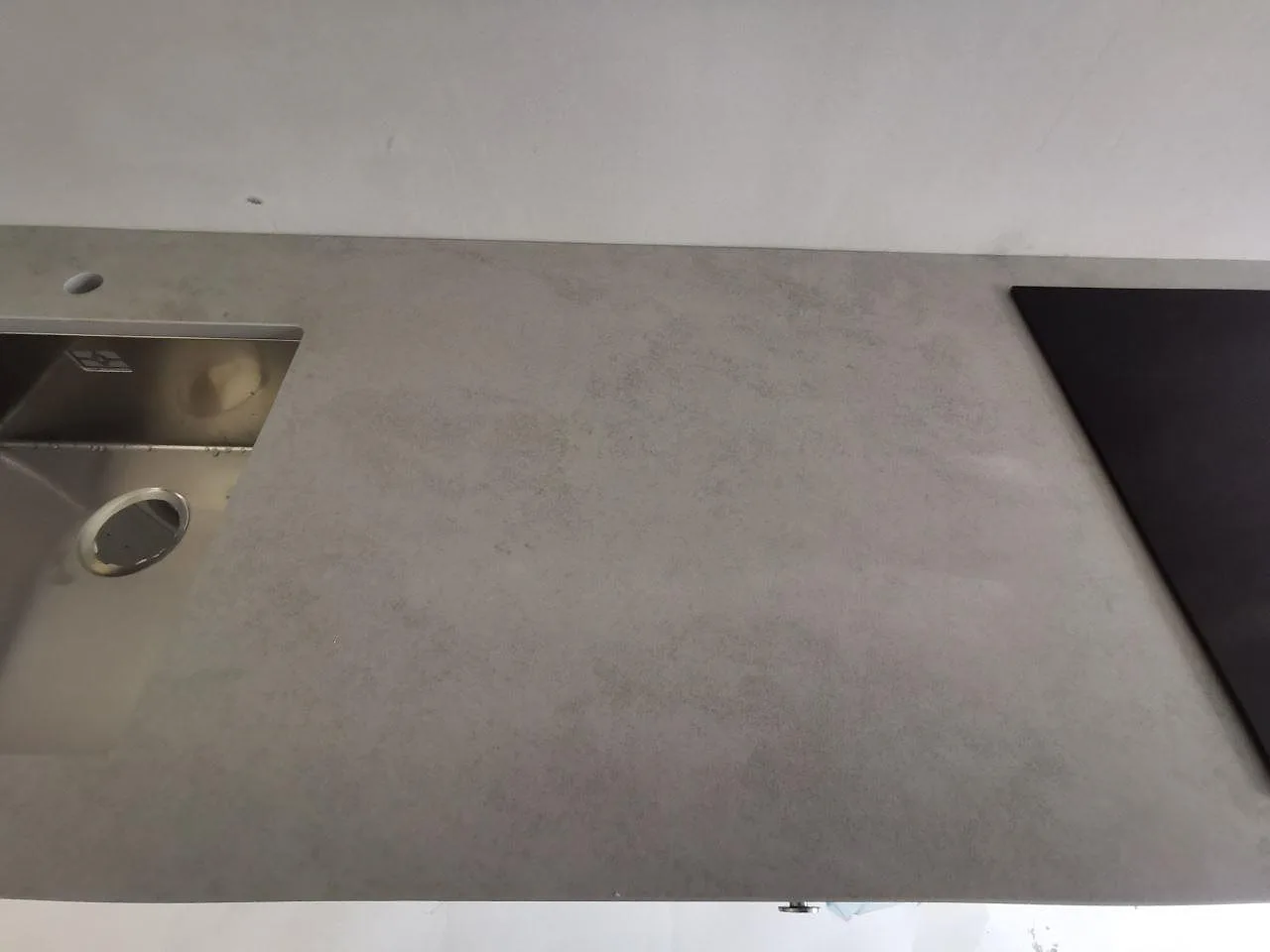 Bänkskiva i Dekton Kovik med underlimmad rostfri diskho till vänster och induktionshäll till höger i ett kök i Malmö.