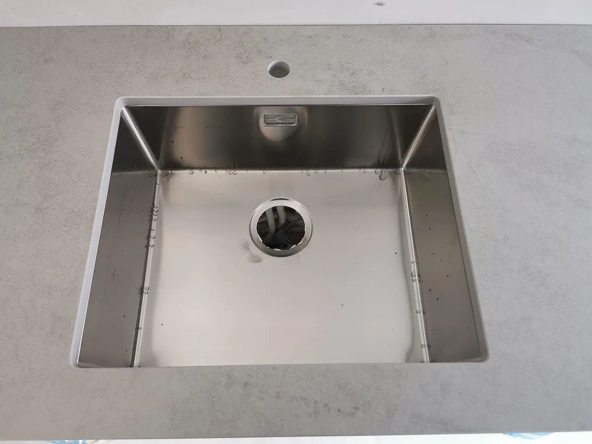 Underlimmad rostfri diskho infälld i bänkskiva av Dekton Kovik i ett kök i Malmö.