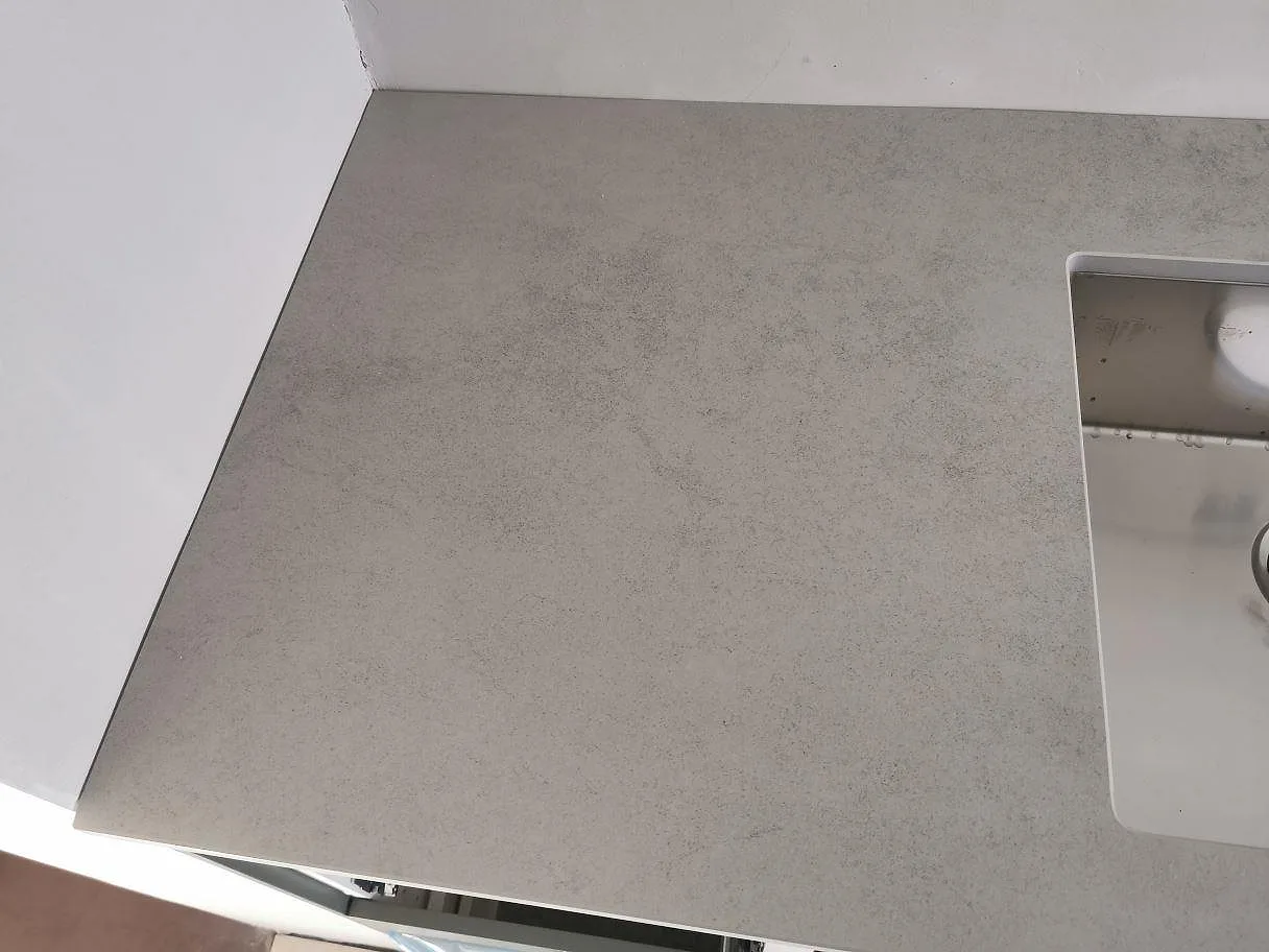 Närbild på den matta betongliknande ytan i Dekton Kovik bänkskiva intill diskhon i ett kök i Malmö.