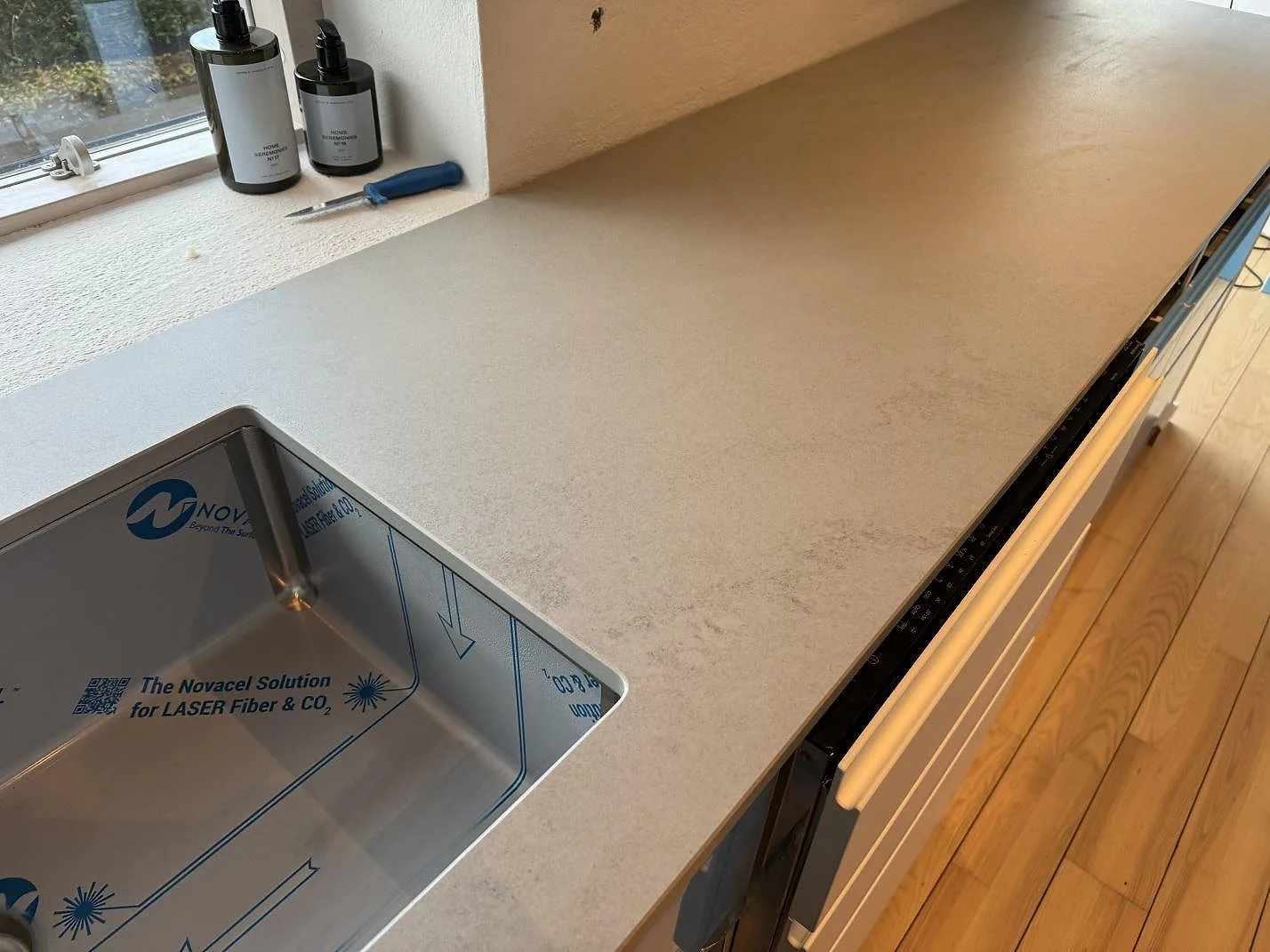 Lång arbetsyta i matt Dekton Kovik med rostfri diskho under stenen och varm träparkett i Rydebäck.