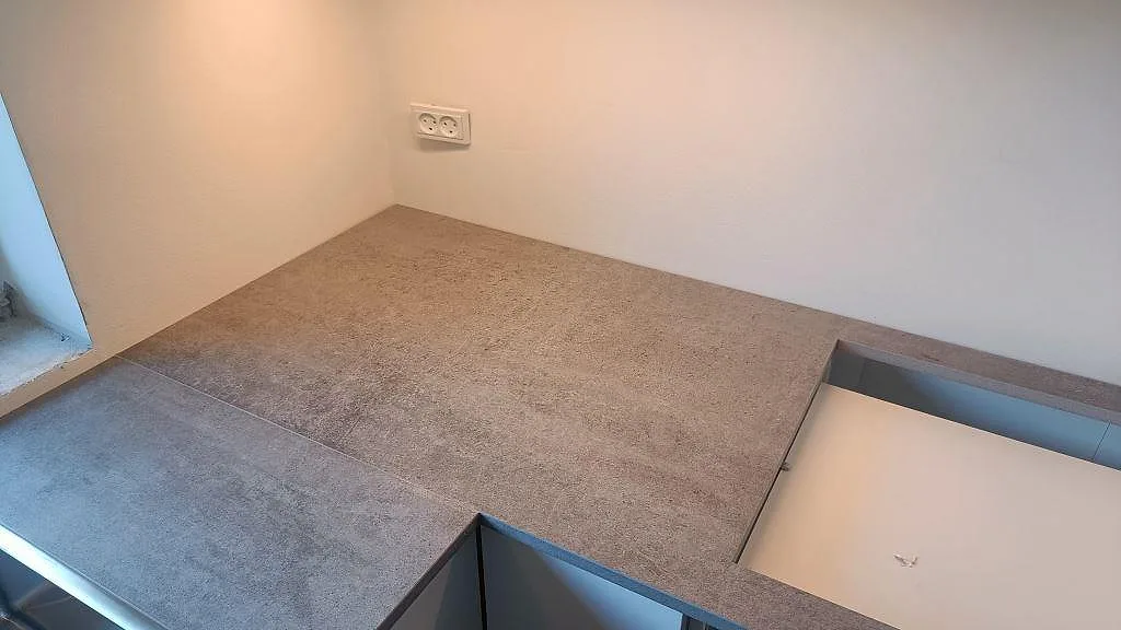 Köksbänkskiva i matt Dekton Kreta keramik med grå cementstruktur, fönsterljus och förberedd öppning i Albertslund.