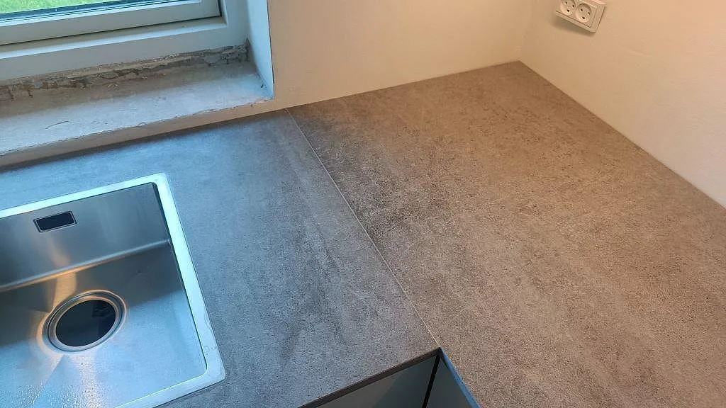 Hörnvy över matt Dekton Kreta keramik med rostfri diskho, fönster och grå bänkyta i Albertslund.