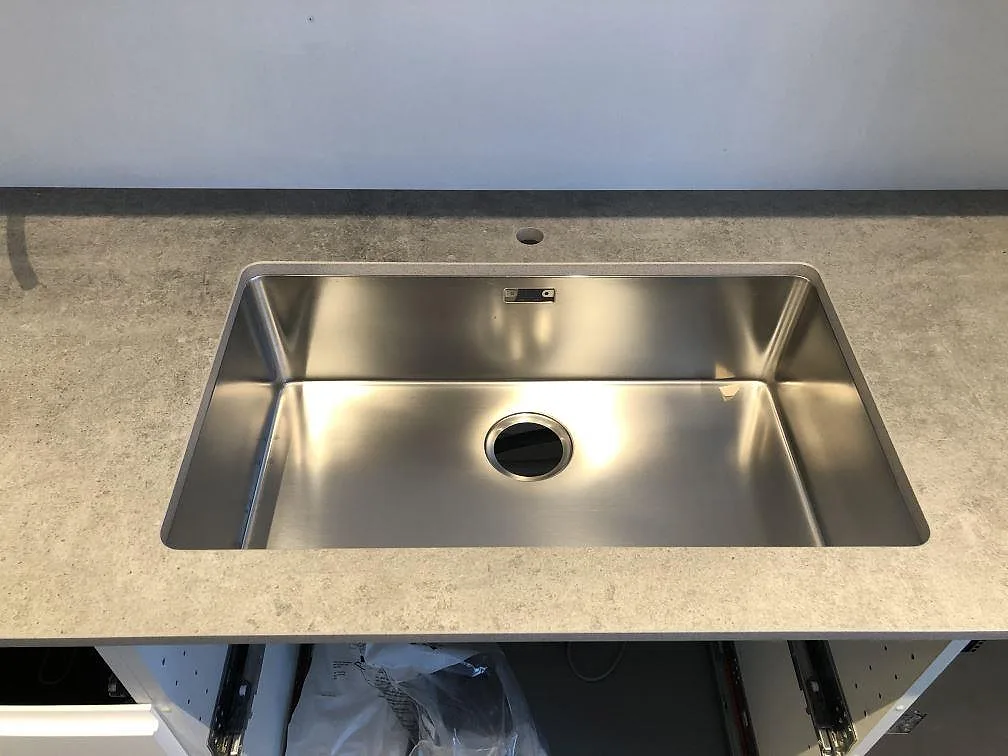 Underlimmad rostfri diskho i en matt ljusgrå Dekton Kreta köksbänkskiva i Hörby.