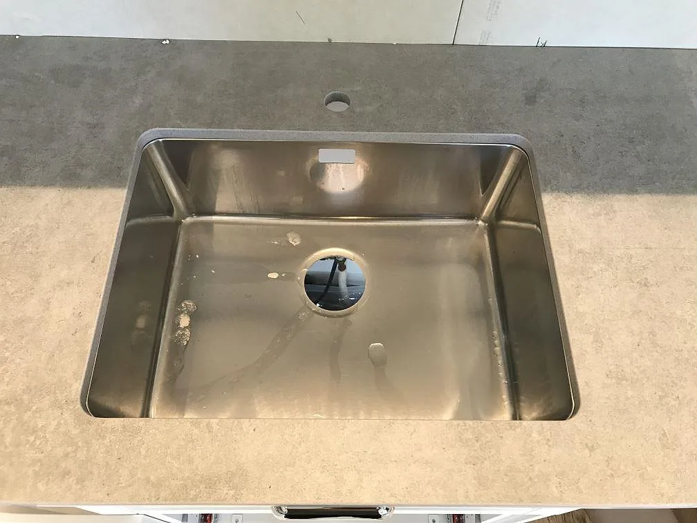 Underlimmad rostfri diskho i en honad Dekton Kreta bänkskiva i grått i ett kök i Karlskrona.