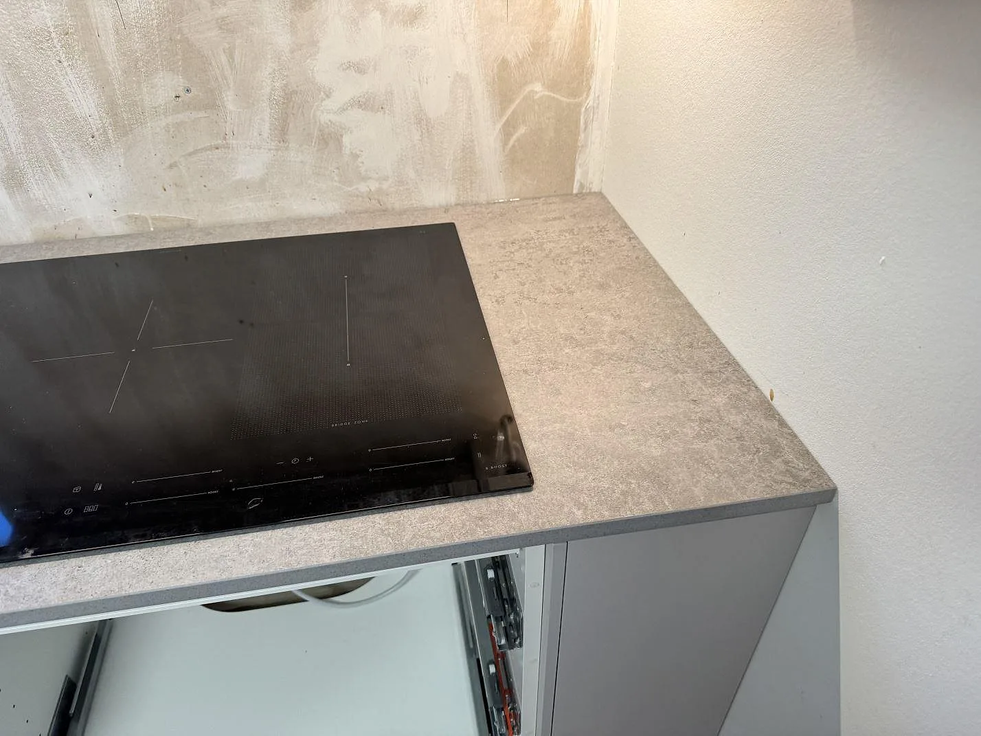 Svart induktionshäll i en matt Dekton Kreta köksbänkskiva med grå betongton i ett kök i Karlskrona.