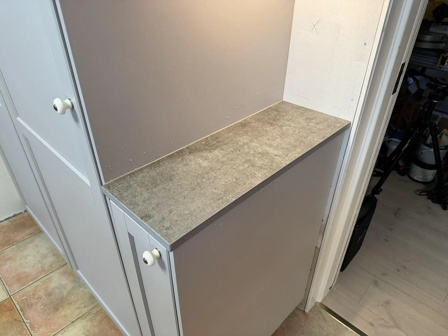 Smal bänkskiva i matt Dekton Kreta, 20 mm keramik, monterad på creamfärgad köksstomme i Karlskrona.